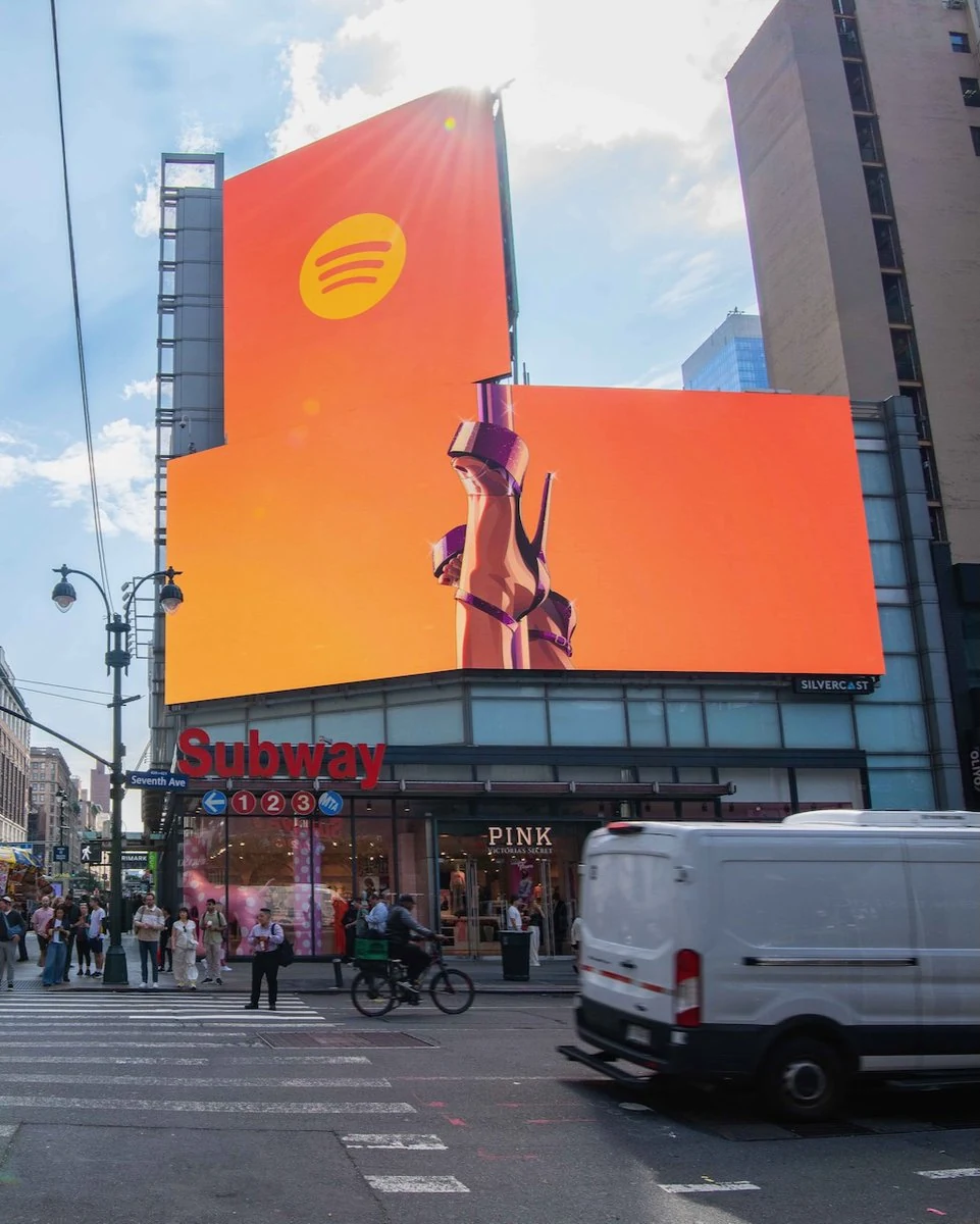Un cartellone digitale arancione con il logo Spotify e un personaggio di GTA VI sopra una strada cittadina.