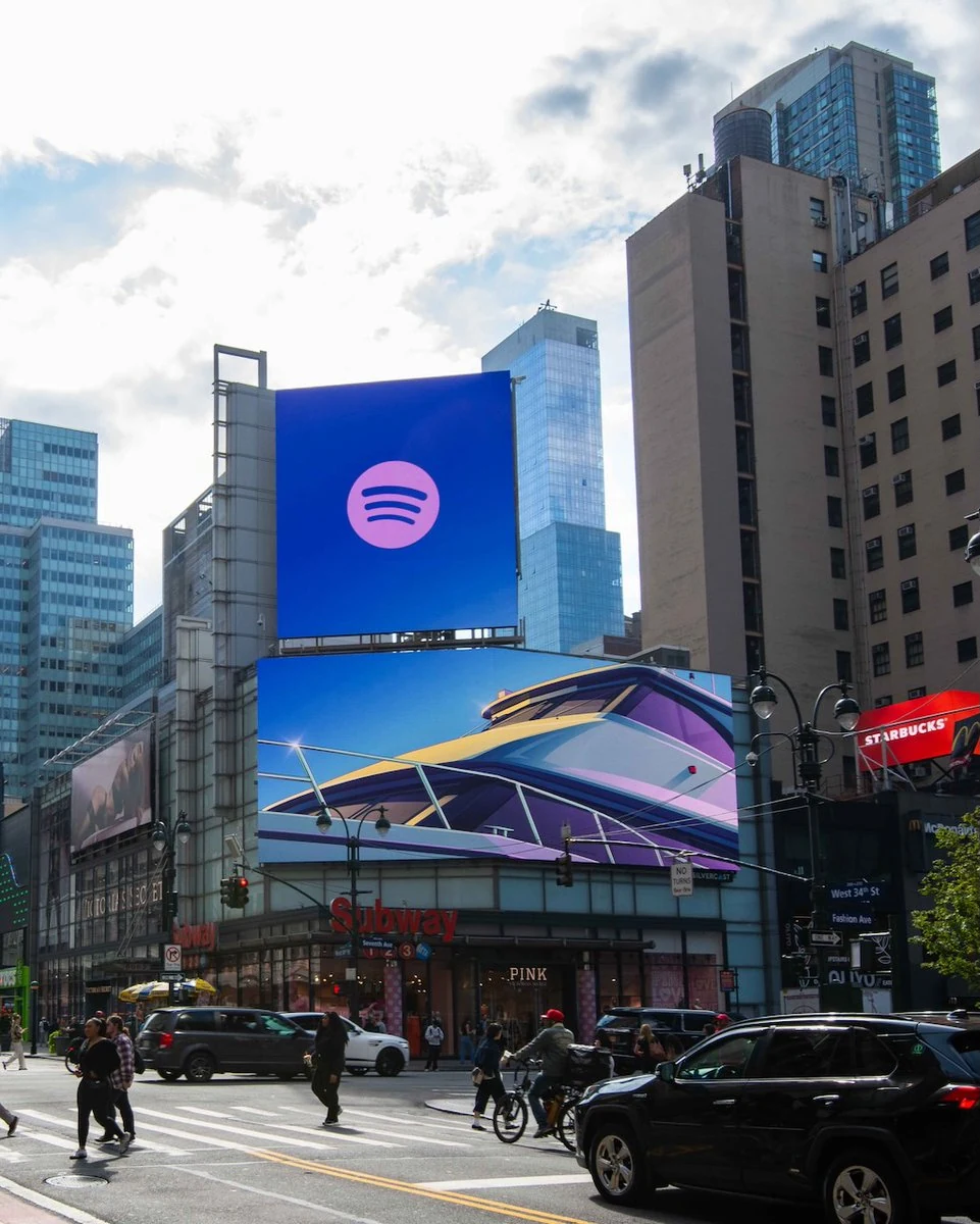 Cartelloni digitali con il logo Spotify e un’illustrazione di GTA VI, affacciati su una strada trafficata.
